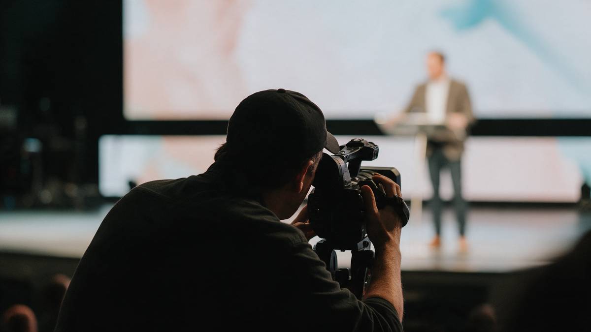 Videographer filming a presenter on stage
